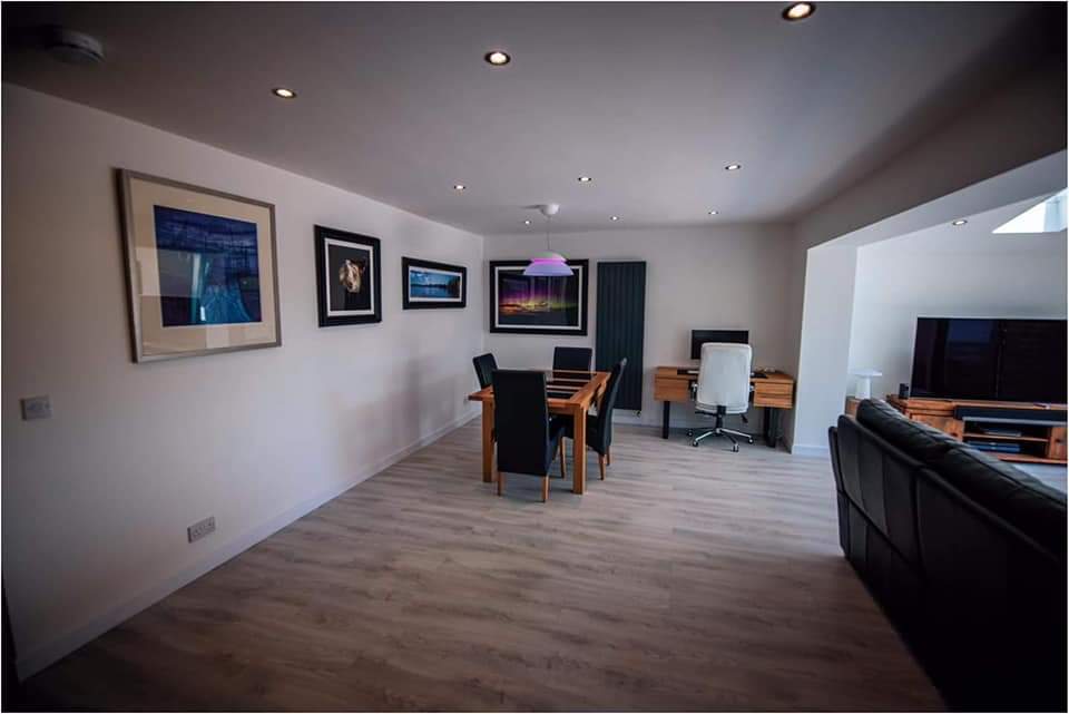 Finished dining and living space inside a completed home extension with downlights and vertical radiator