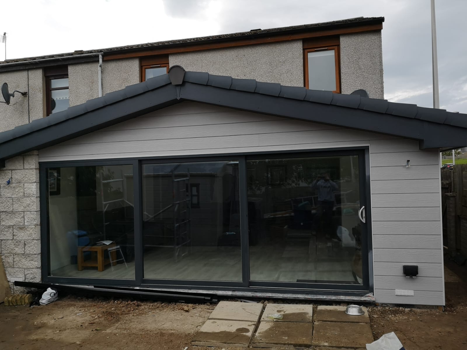 Completed single-storey rear extension with grey cladding and anthracite sliding doors