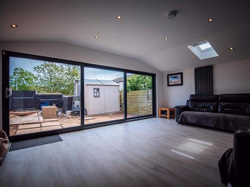 Finished living space inside a completed home extension and refurbishment in Aberdeen, with wide sliding doors and a Velux rooflight